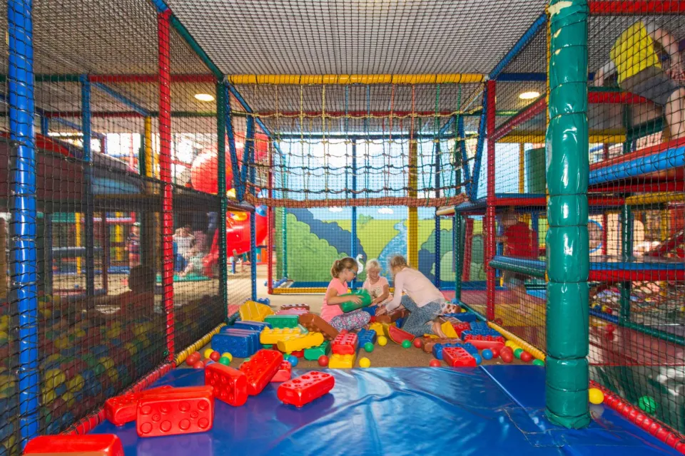 Kinderen spelen in de ballenbak van een kleurrijke overdekte binnenspeeltuin in de omgeving van Drentse Vennen