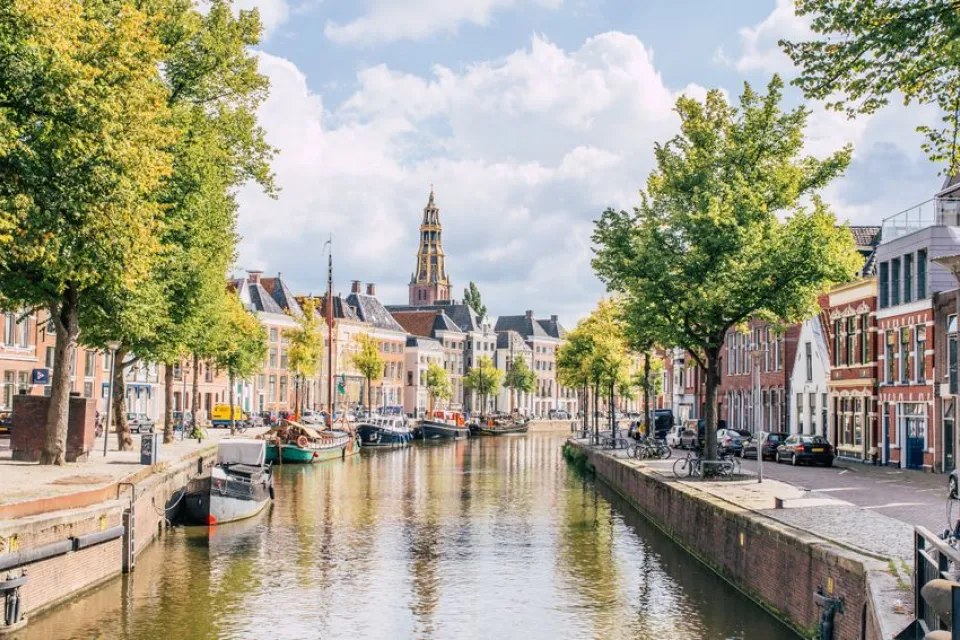 Gracht met bootjes, bomen en historische gevels in de binnenstad van Groningen