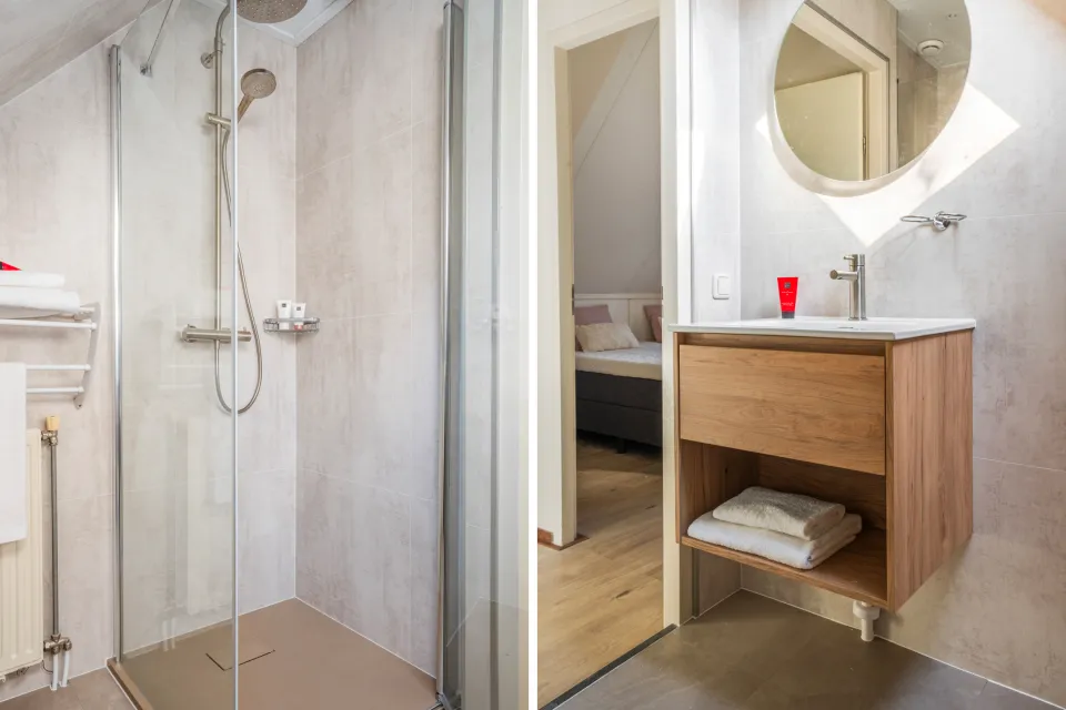 Badkamer met inloopdouche, houten wastafelmeubel en spiegel in een vakantiewoning op Drentse Vennen