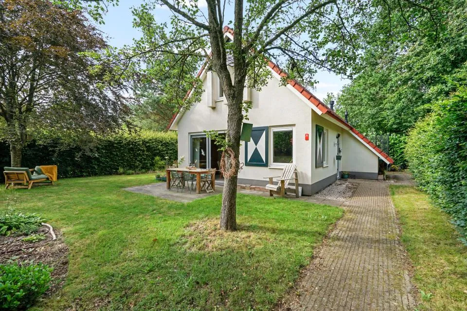 Witte vakantiewoning Valk 36 met rood dak, terras met tuinset en een grote boom in de tuin