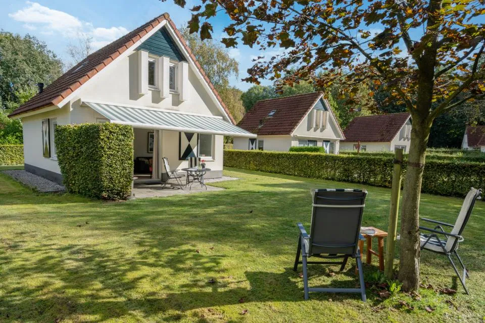 Witte vakantiewoning Valk 45 met veranda, ligstoelen op het gazon en hagen rondom