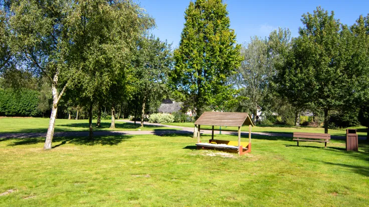 Houten picknicktafel en een bankje op een grasveld tussen de bomen op vakantiepark Drentse Vennen