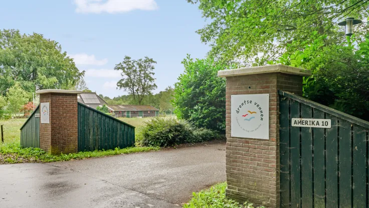 Entree van vakantiepark Drentse Vennen met een groen toegangshek, naambord en oprit